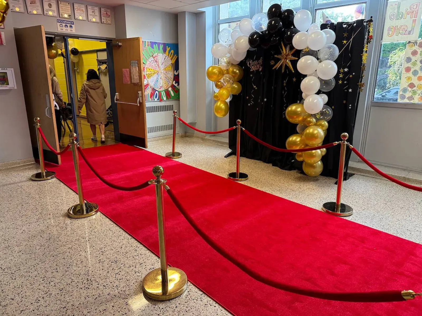 Gold rope stanchions with red velvet ropes along an indoor red carpet runner